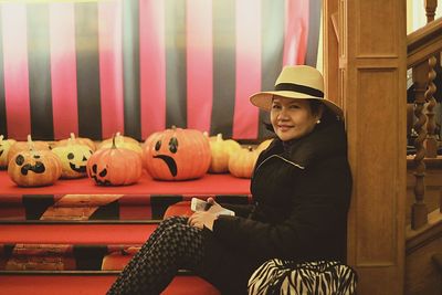 Side view portrait of woman sitting by jack o lanterns