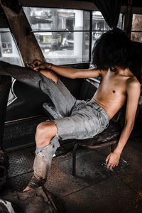 Full length of woman sitting on abandoned window