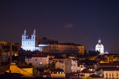 Illuminated buildings in city against sky at night