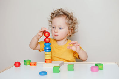 Toddler playing with learning toy pyramid stacking blocks at home. early age education
