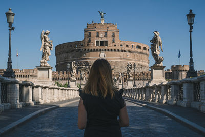 Rear view of woman standing against statue in city