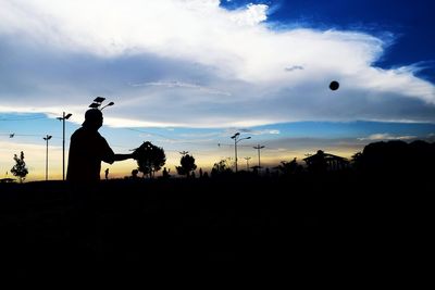 Silhouette man playing on field against sky during sunset