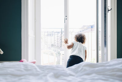 Rear view of woman walking on bed at home