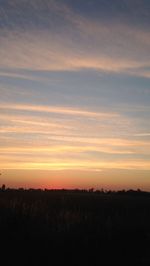 Scenic view of silhouette field against sky during sunset