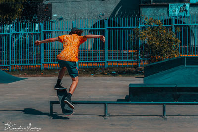 Full length rear view of a boy jumping against built structure