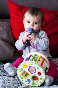 Cute baby girl sitting on sofa at home