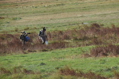 Two people riding horse on field