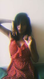 Portrait of young woman standing against wall