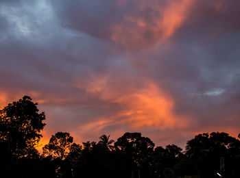 Low angle view of silhouette trees against dramatic sky