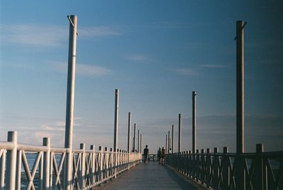 Rear view of people walking on bridge against sky