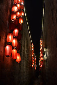 Low angle view of illuminated lanterns hanging against wall