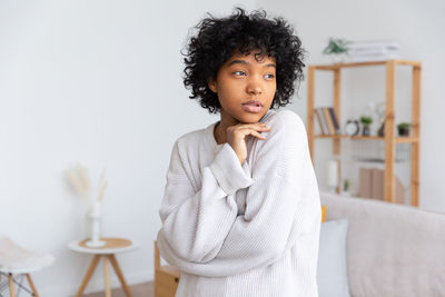 Portrait of young woman looking away against white background