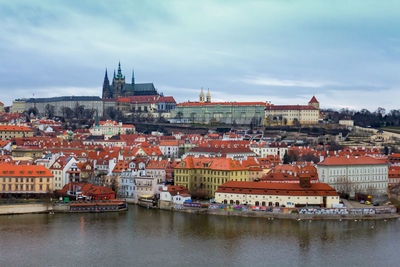 Buildings by river against sky in city