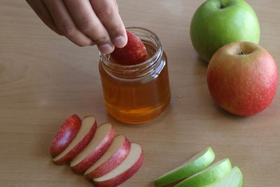 Close-up of hand holding apple on table