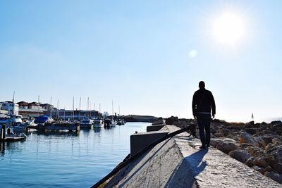 Man standing on boat moored in sea against clear sky
