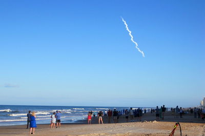 People on beach against blue sky