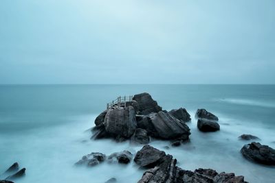 Scenic view of rock formations in sea against sky