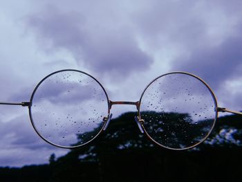 Close-up of water drops on sunglasses against sky