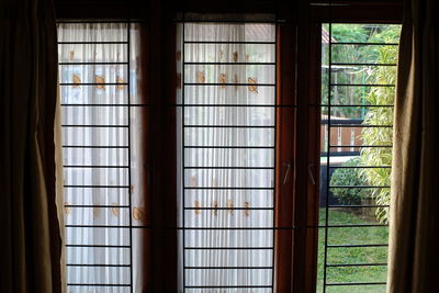 Light curtains on a window, one part of which is open, showing a garden view on the outside