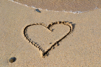 Heart shape on sand at beach during sunny day