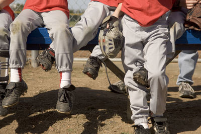 Boys legs intertwined on a baseball bench