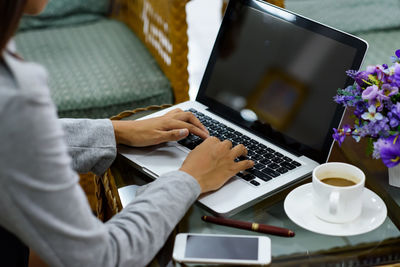 Midsection of woman using laptop on table
