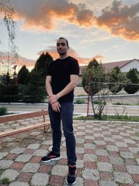 Full length portrait of young man standing against sky during sunset