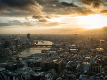 High angle view of thames river amidst cityscape against cloudy sky