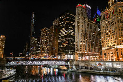 Illuminated buildings by river at night