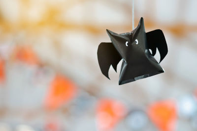 Origami bat made of black paper, isolated on glass window or door background. 