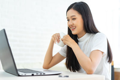 Young woman using phone while sitting on table