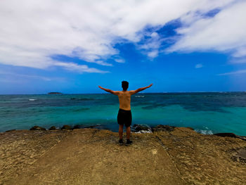 Full length rear view of man standing on sea shore against sky