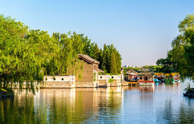Buildings by river against clear blue sky