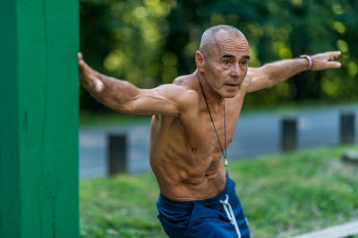 Full length of shirtless man exercising in park