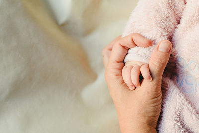 Cropped hand of mother holding baby girl hand