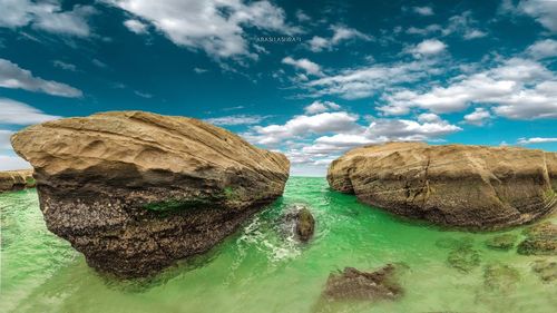 Panoramic view of rocks and sea against sky