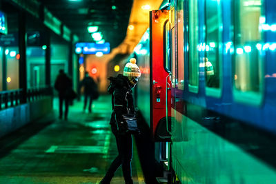 Full length of woman walking on illuminated road at night