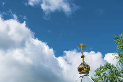 Low angle view of cross by building against sky