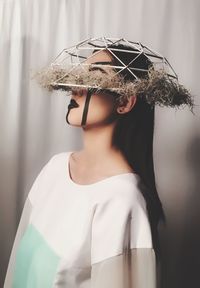 Woman wearing basket by curtain at home