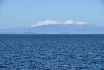 Scenic view of sea and mountains against blue sky