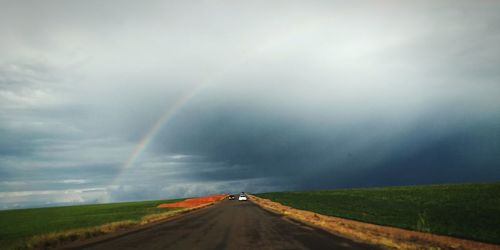 Rainbow over road against sky