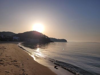 Scenic view of beach against clear sky during sunset