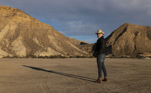 Adult man in cowboy hat standing against mountains in tabernas desert. almeria, spain