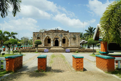 Gazebo by palm trees against sky