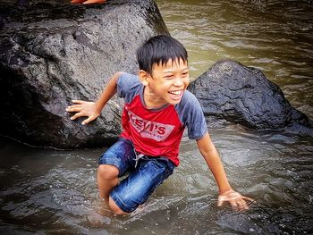 Full length of happy boy on rock at shore