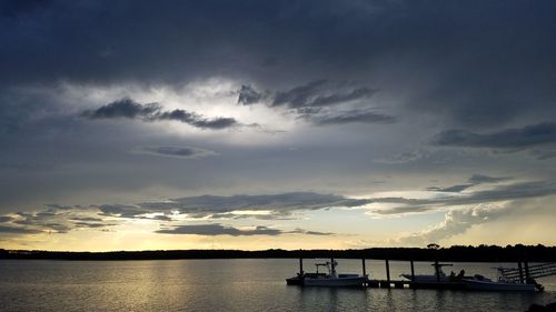 Silhouette boats in sea against sky during sunset