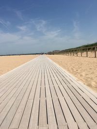 Surface level view of wooden boardwalk on beach against sky in normandy 