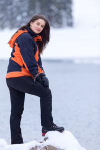 Young woman standing on snow against sky