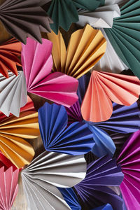 Close-up of multi-colored paper origami hearts layered on wood