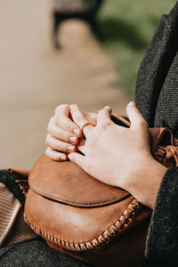 Midsection of woman wearing ring sitting on bench outdoors